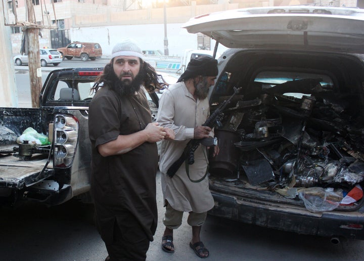 Fighters from the Islamic State group load a van with parts that they said was a US drone that crashed into a communications 