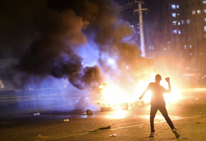 A youth prepares to throw a stone as pallets burn during clashes between Turkish riot policemen and Kurdish protesters in the southeastern city of Diyarbakir on Nov. 1, 2015 after first results of the Turkish general election showed a clear victory to the AKP.