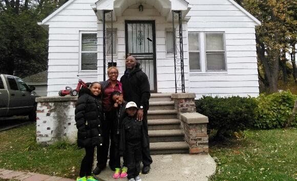 Tynetta Sneed, her three children and her fiancé stand in front of their home in northwest Detroit. 