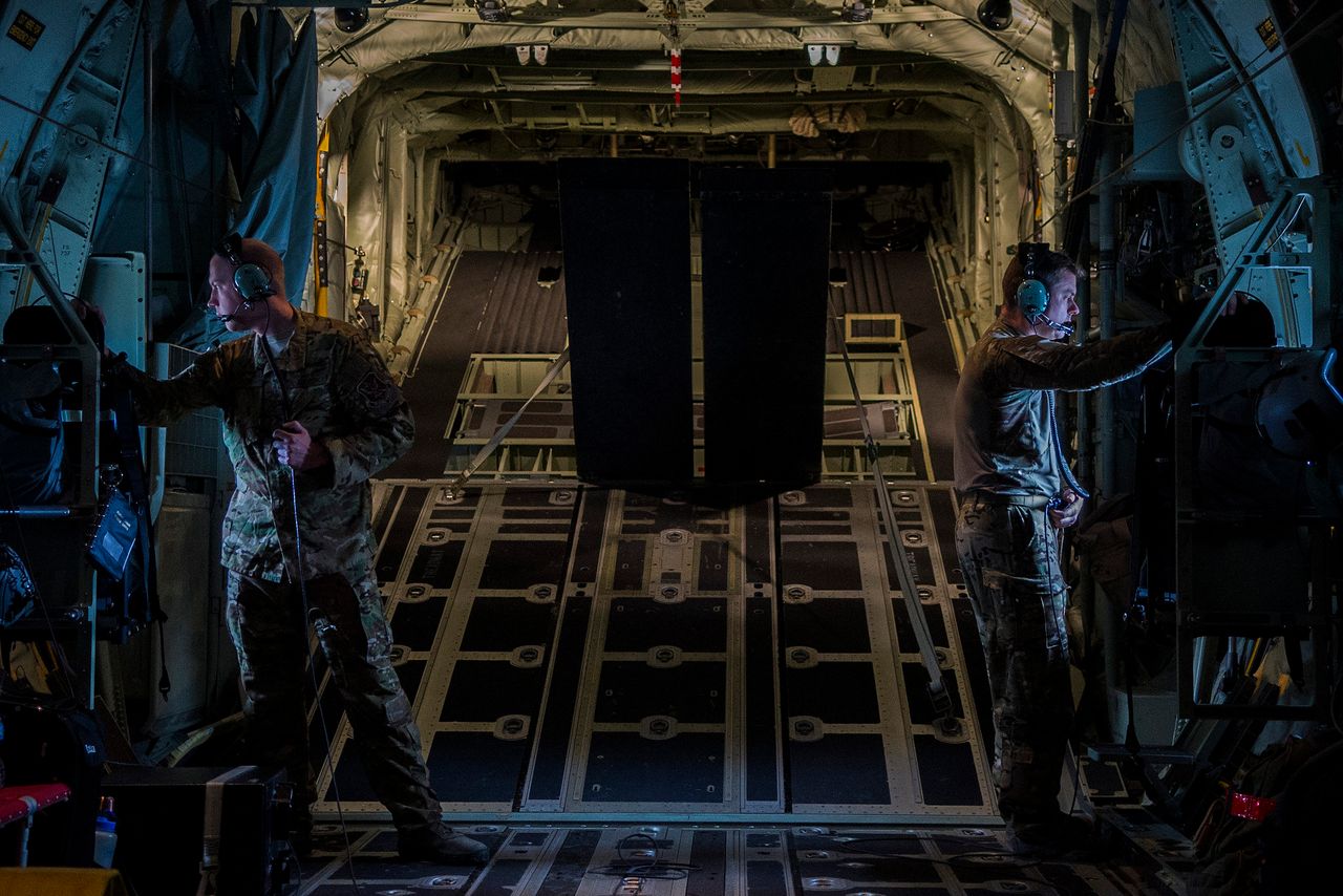 Two Airmen, assigned to the 71st Rescue Squadron at Moody Air Force Base, Ga., look out the windows of a C-130J Super Hercules during rescue and refueling training near Beja Air Base, Portugal, Oct. 23, 2015.
