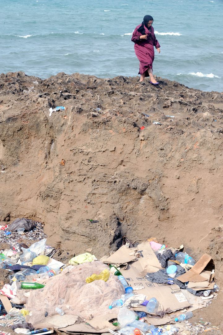 A Moroccan woman walks past trash near the polluted coastline of Rabat on September 28, 2012.