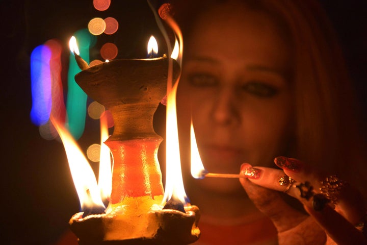 An Indian woman lights an earthen lamp in Amritsar on November 10, 2015 on the eve of the Indian festival of Diwali. 