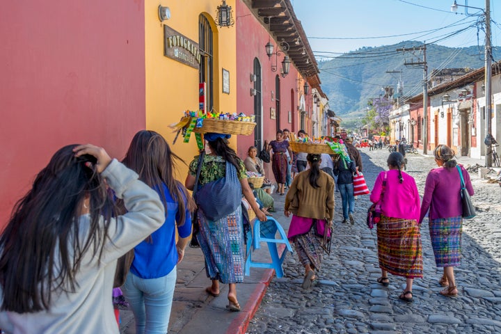 Women carrying baskets on their head while walking down the street in Antigua Guatemala.