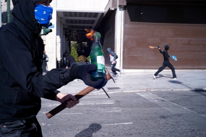 Riot police were seen firing tear gas at dozens of black-clad people who hurled petrol bombs and stones and smash shop w