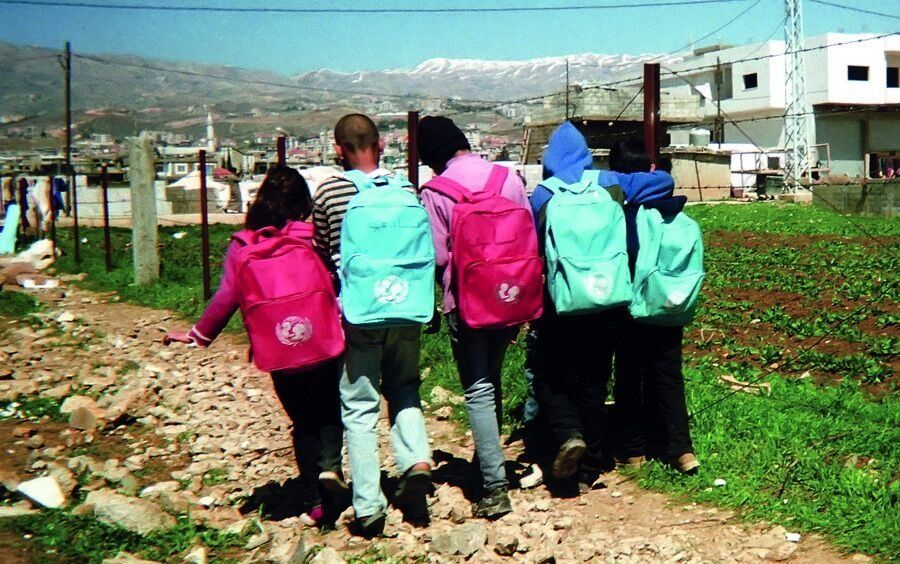 Shot by Ghazi, age 10, from al-Qasir, Syria. A group of children walking to school wearing UNICEF backpacks in the Bekaa Valley, Lebanon, in 2014.