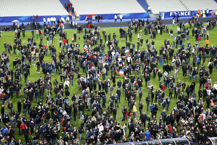 Spectators wait on the pitch of the Stade de France stadium in Seine-Saint-Denis, Paris' suburb on November 13, 2015 after a series of gun attacks occurred across Paris. 