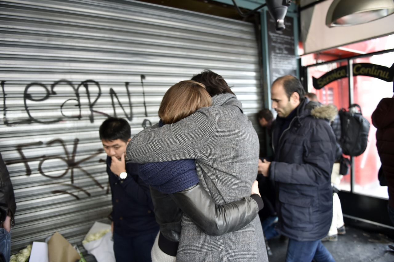 People hug each other and place flowers and candles outside the cafe La Belle Equipe on the Rue de Charonne in Paris on Nov. 14, 2015, following a series of coordinated attacks in and around Paris late Friday.