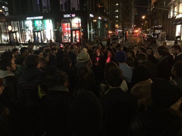 French exchange students huddle closely in New York's Union Square, some holding lit candles.