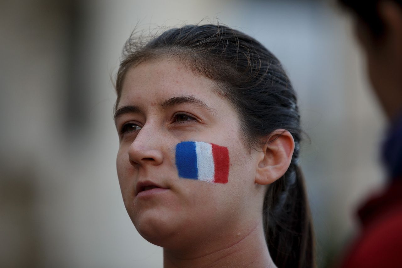 A woman with a French flag painted on her face looks on after a minute of silence in tribute to the victims of Friday's Paris attacks at Madrid's Town Hall on Nov. 14, 2015.