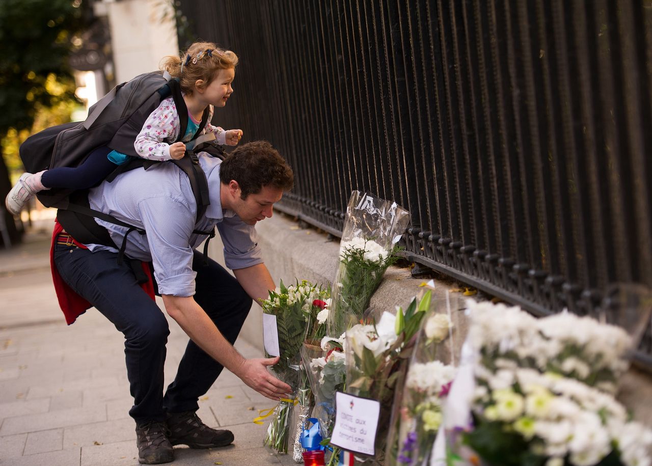 A father and daughter pay their respects to the victims of the Paris attacks at the entrance to the French consulate on Nov. 14, 2015 in Madrid, Spain.