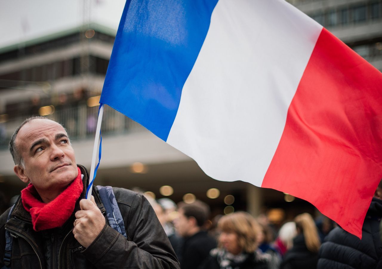A man holds a French flag during a solidarity gathering in Stockholm a day after deadly attacks in Paris on Nov. 14, 2015.