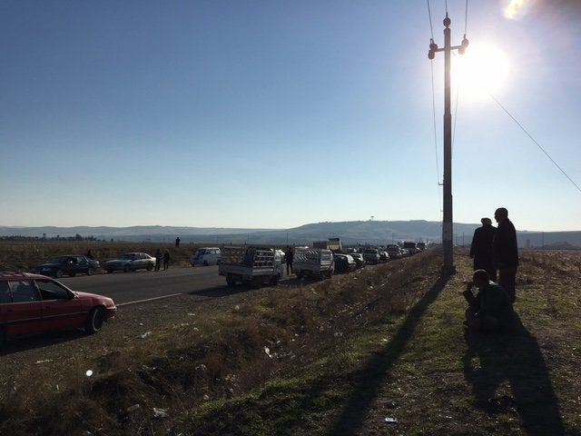 Yazidi men stand on the side of a main road leading to Sinjar, waiting for permission to enter the city that was recently fre