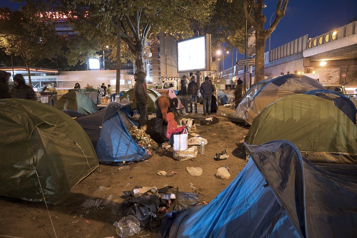 Migrants and refugees, mainly from Syria, prepare to leave their makeshift camp early on Oct. 2 after being evicted by French authorities from the area set up at the Porte de Saint-Ouen in northern Paris.