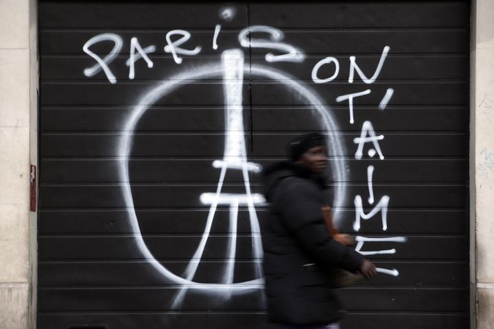 A woman walks past a shuttered shop with graffiti that reads "Paris we love you" in central east Paris on November 15, 2015. The graffiti is reminiscent of an image created by French designer Jean Jullien as a symbol of peace following Friday's terror attacks.