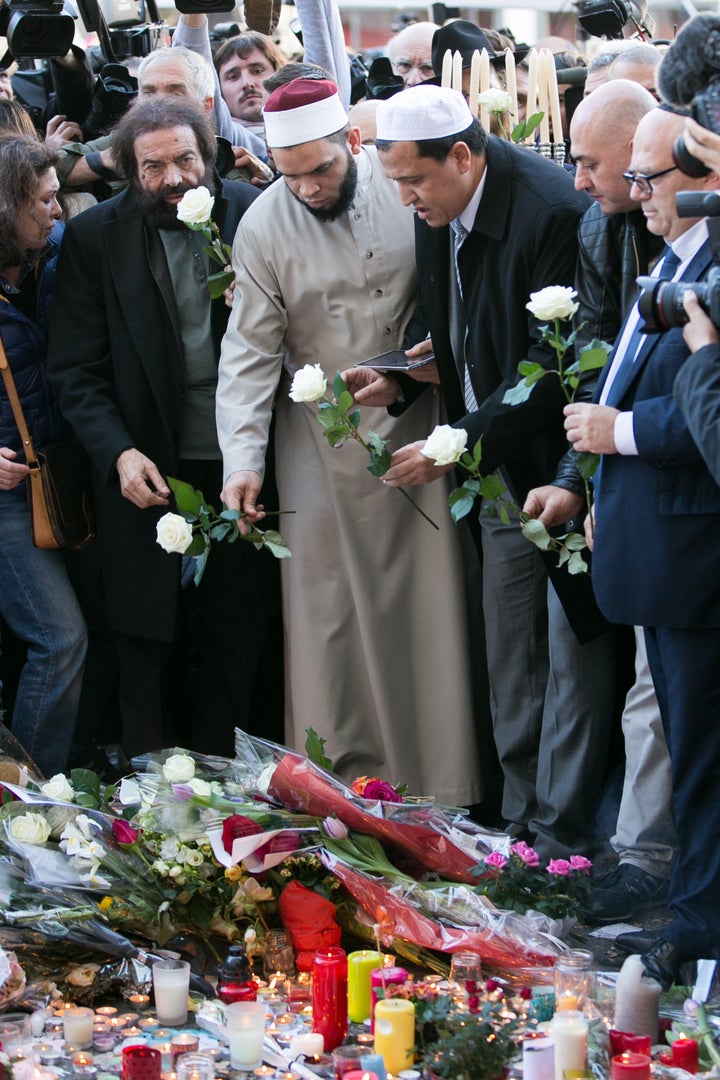 Author Marek Halter (L), Imam Hassen Chalghoumi (3rd from L), and Imam Hocine Drouiche (R) gather at a makeshift memorial near the Bataclan theatre in Paris on Sunday.