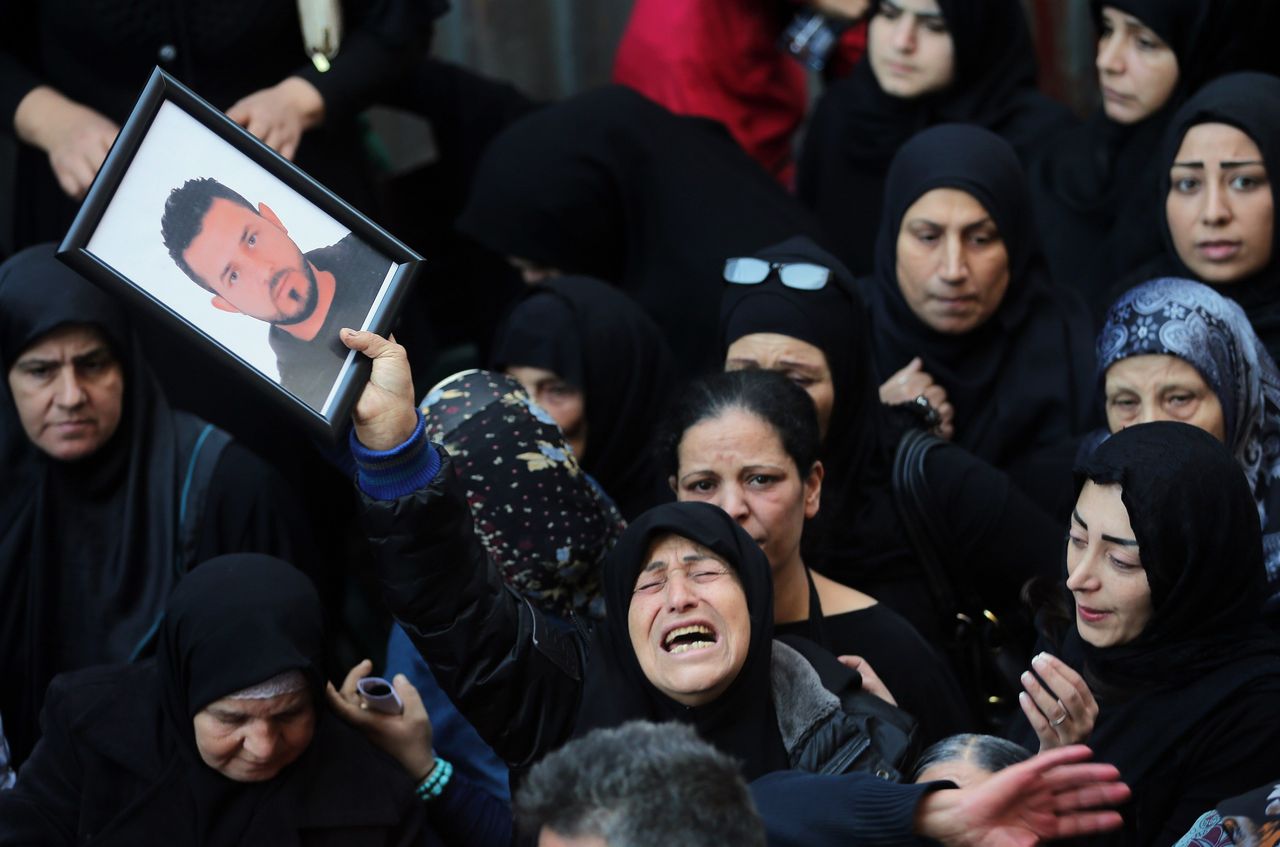 A relative of Samer Huhu, who was killed in a twin bombing attack that rocked a busy shopping street in the area of Burj al-Barajneh, waves his portrait as she mourns during his funeral in the southern suburb of the capital Beirut on November 13, 2015. Lebanon mourned 44 people killed in south Beirut in a twin bombing claimed by the Islamic State group, the bloodiest such attack in years, the Red Cross also said at least 239 people were also wounded, several in critical condition.
