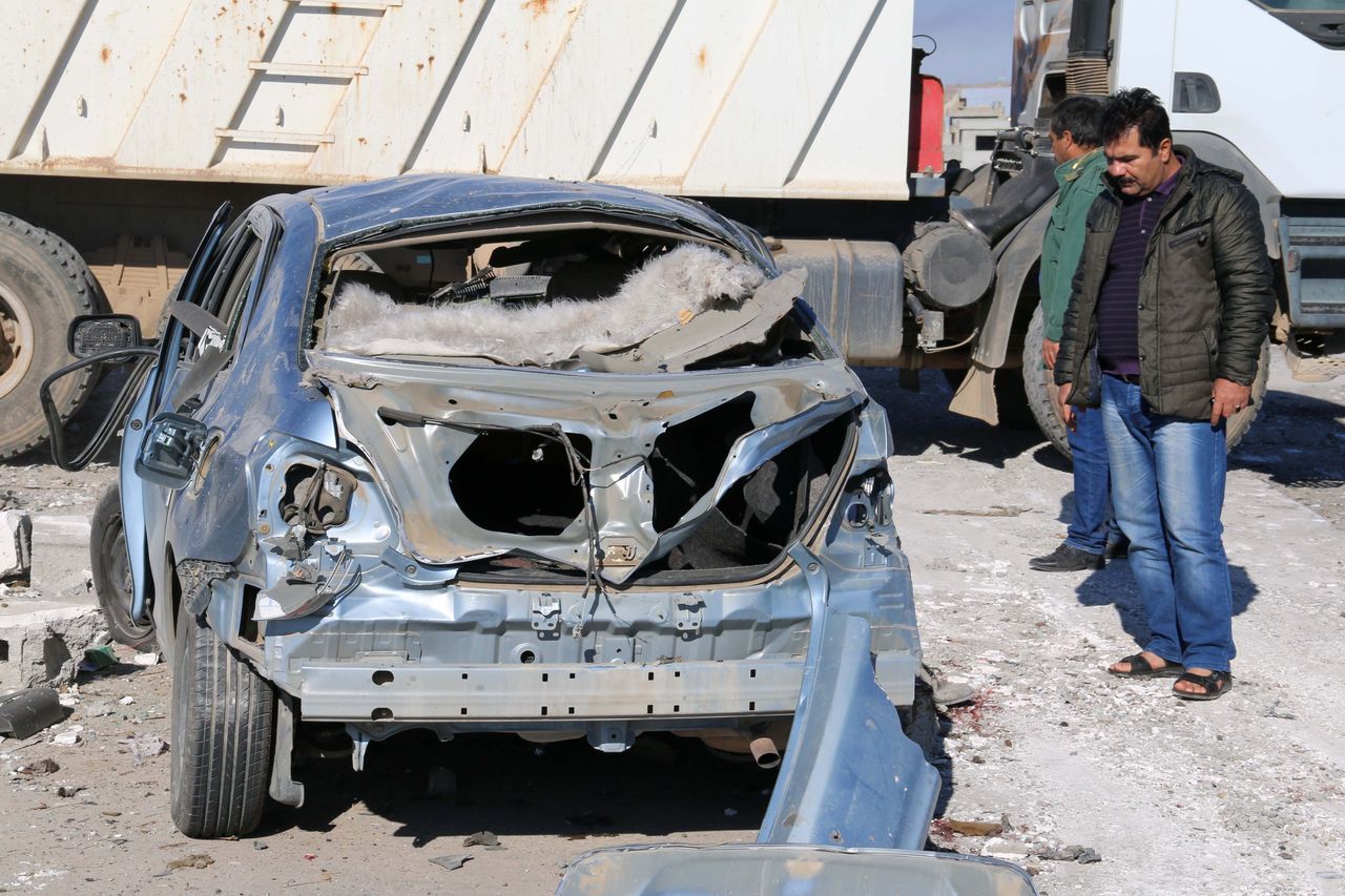 Iraqi men stand next to the wreckage of a car on November 4, 2015, in the aftermath of a suicide bombing by militants of Islamic State jihadist group at a checkpoint at the entrance of the Dibis area, northwest of the Kirkuk provincial capital. 