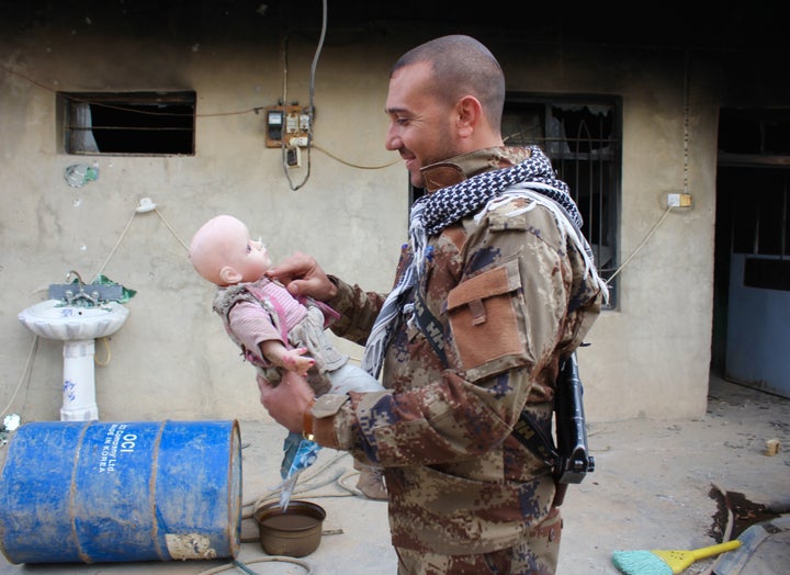 A member of the Asayesh security forces picks up a doll he gave to his daughter. ISIS destroyed his home in Sinjar, Iraq.