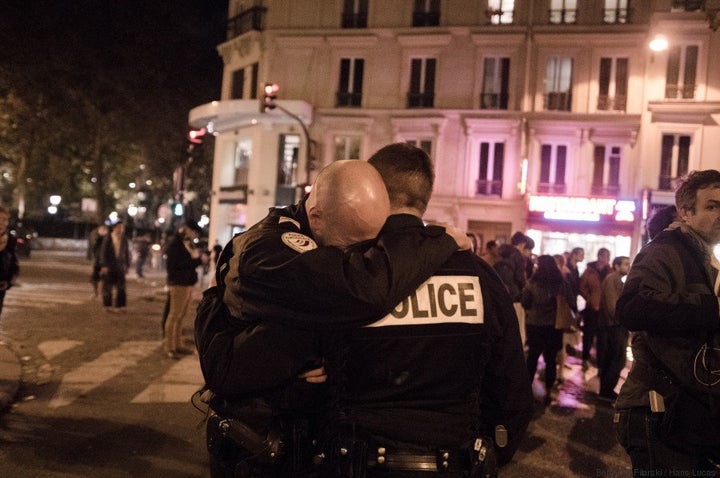 A policeman buries his head in another policeman's shoulder while in Paris' 11th arrondissement on Sunday, Nov. 15,