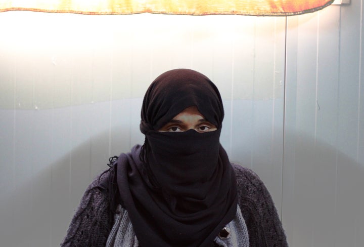 A Yazidi woman who escaped ISIS enslavement sits in the caravan she now calls home after ISIS took over and destroyed he