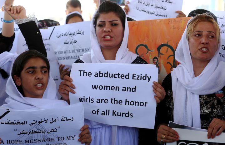 Iraqi Yazidi women hold placards during a protest outside the United Nations (UN) office in the Iraqi city of Arbil, the capital of the autonomous Kurdish region, on August 2, 2015 in support of women from their community who were kidnapped last year in the Sinjar region by the Islamic State (IS) group jihadists. In 2014, the jihadists massacred Yazidis, forced tens of thousands of them to flee, captured thousands of girls and women as spoils of war and used them as sex slaves.
