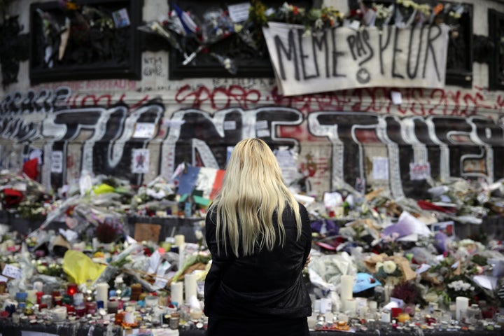 A woman stands in front of a makeshift memorial made up with flowers, candles and messages, on November 17, 2015, at the Place de la Republique square in Paris, in tribute to victims of the attacks claimed by Islamic State which killed at least 129 people and left more than 350 injured on November 13 in Paris.