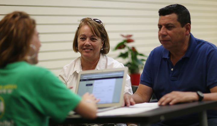 Elvira Lopezto (center) and Pedro Salavarria Carrasco (right) speak with an insurance agent from Sunshine Life and Health Advisors at a store setup in the Mall of the Americas on Nov. 2, in Miami.