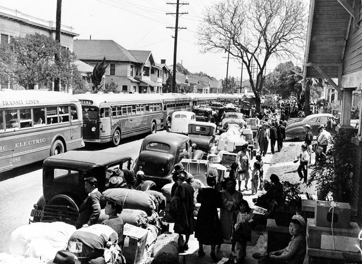 This 1942 photo shows the evacuation of American-born Japanese civilians during World War II, as they leave their homes for internment, in Los Angeles, California. The sidewalks are piled high with indispensable personal possessions, cars and buses are waiting to transport the evacuees to the war relocation camps.