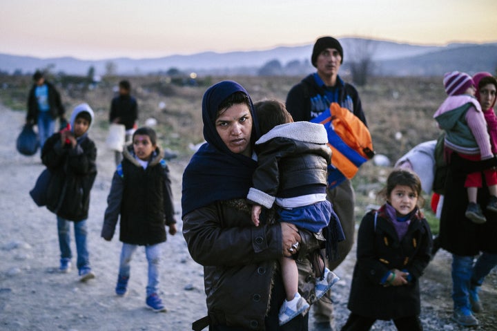 A woman carries a child as migrants and refugees walk near Gevgelija, Macedonia, after crossing the Greece-Macedonia border on Nov. 18.