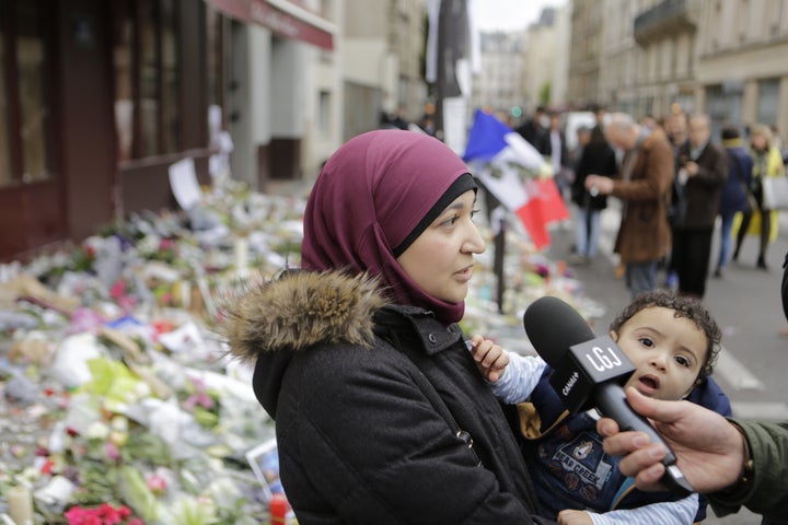 A Muslim woman is interviewed as she is paying her respects at the memorial outside Le Carillon for the people killed here during the Paris attacks.