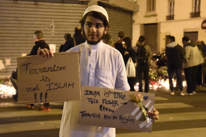 A Muslim holds placard reading 'Terrorism is not Islam. Islam is like this flower. Terrorism has no religion' during a gathering at Le Carillon, one of the sites of the Paris attacks, on November 15, 2015.