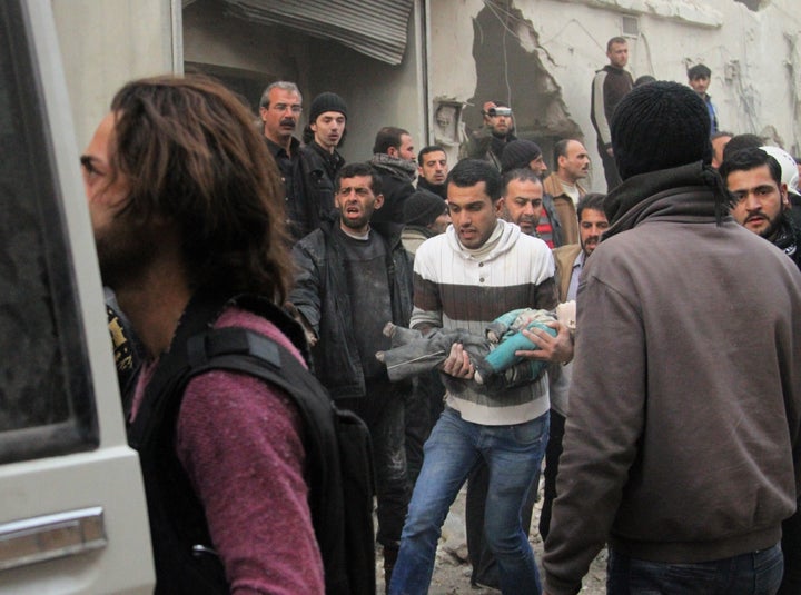 A Syrian man carries a child's body after Syrian regime barrel bomb attacks on Feb. 2, 2014, in Aleppo. T