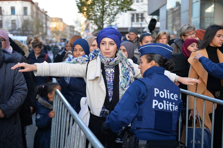 Police also carried out fresh raids in Molenbeek neighborhood in Brussels, where at least two of the attackers lived. In this photo, a police officer frisks a woman as she arrives for a candlelight vigil for the Paris attack victims in Molenbeek Wednesday.