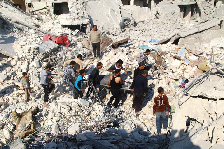 People with a rescue team inspect a collapsed building and try to rescue people after an Assad-ordered airstrike over residential areas in Aleppo, Syria, on Oct. 31, 2015.