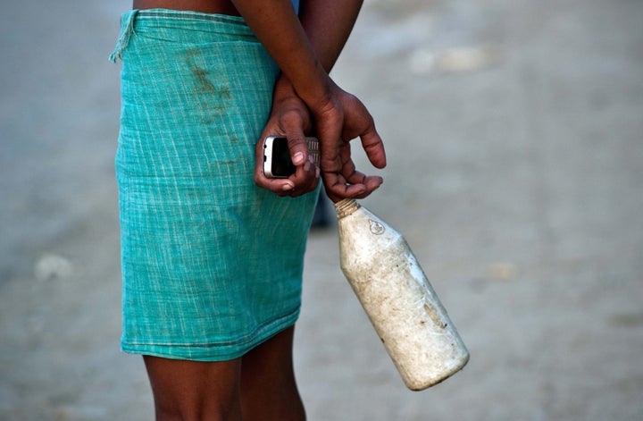In this photograph taken on August 31, 2014, an Indian resident chats to others on his way home after defecating in an open f