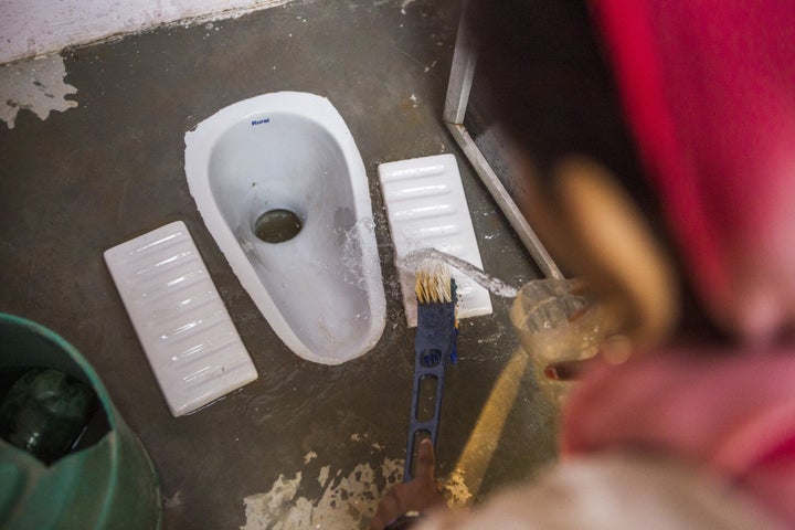 A resident cleans a toilet block, recently built by villagers with support from Sulabh International Social Service Organisat