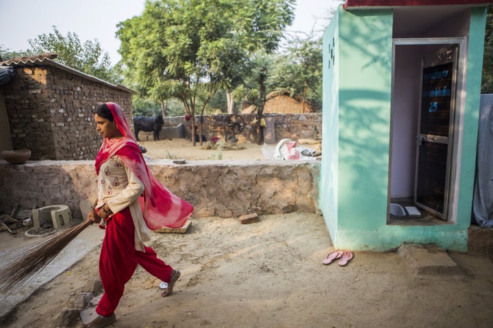 A resident walks away after cleaning a toilet block, recently built by villagers with support from Sulabh International Socia