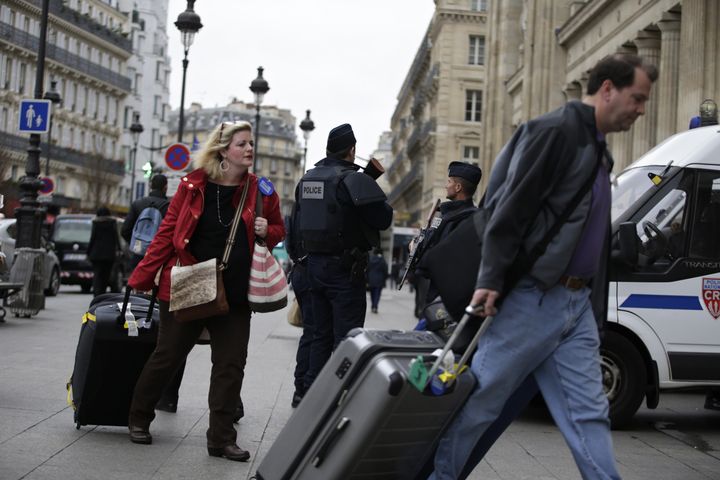 Travellers (L and R) walks past policemen standing guard outside the Gare du Nord railway station on November 16, 2015 in Paris, three days after the terrorist attacks that left over 130 dead and more than 350 injured.