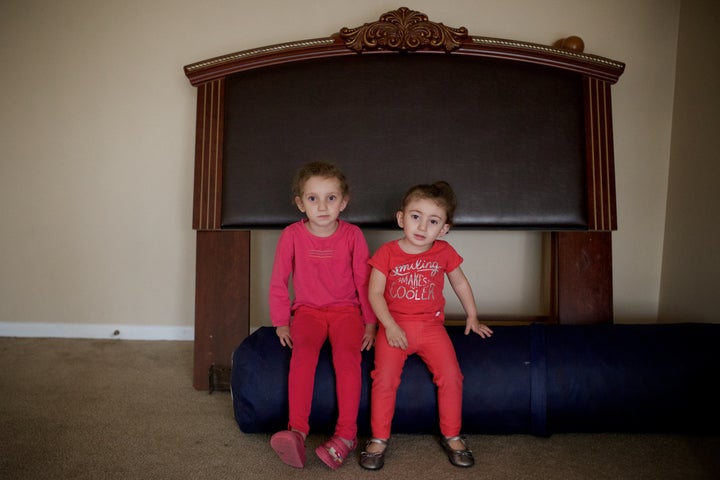 Syrian refugees Hiam Alawad, left, 4, and Dana Alawad, 2, sit by a bed backboard in their new home in Bloomfield Hills, Michigan on Nov. 16, 2015.