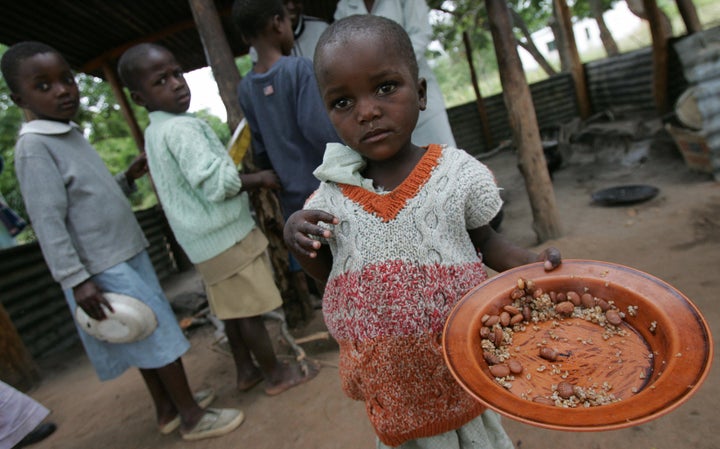 Bikita, ZIMBABWE: Zimbabwean children eat 02 April 2007 at the Masarira primary school, where about 30 pupils receive a daily ration of beans and starch-based cereals during their mid-morning break. For some it is the only meal they will have in the day, said headteacher Zvinavashe Takabvirakare.