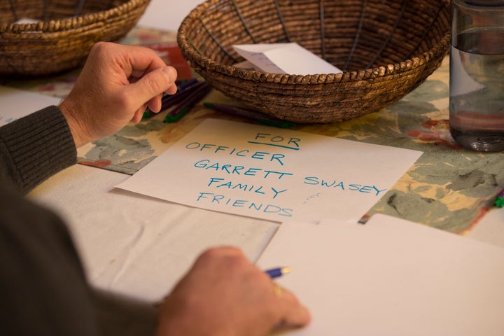 People write notes for Officer Garrett Swasey family and friends and Planned Parenthood before a vigil at the All Souls Unita