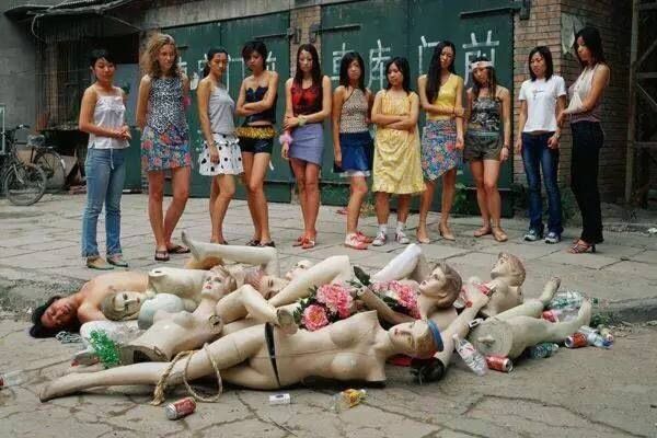 A photo by Liu Jin depicting women staring at broken manikins and a topless man.