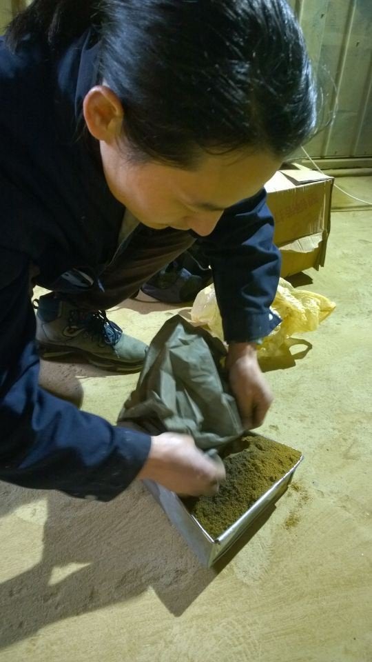 Wang mixes the pollution particles he collected with some clay to make into a brick.