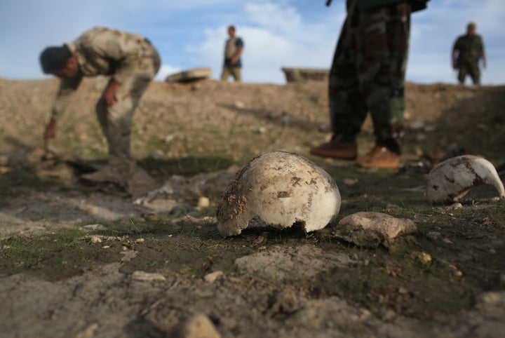 Members of the Kurdish military investigate a mass grave they say contains the remains of more than 50 Yazidis who were killed by ISIS in Sinjar, Iraq. They have discovered at least six mass graves in the area.