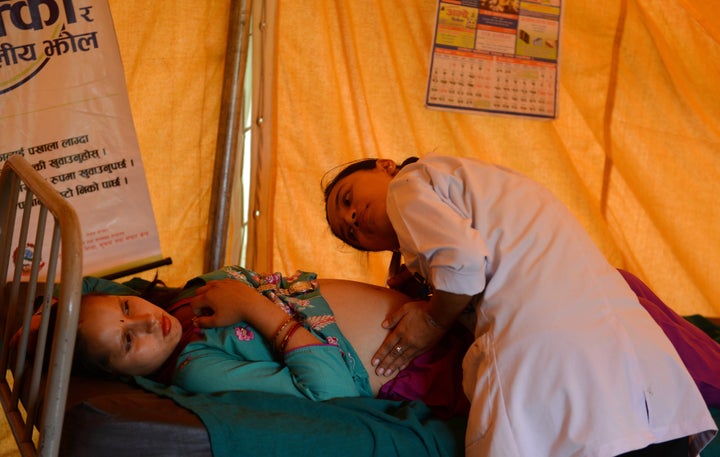 In this photograph taken on July 15, 2015, a Nepalese villager is monitored by a health worker at a makeshift birthing centre
