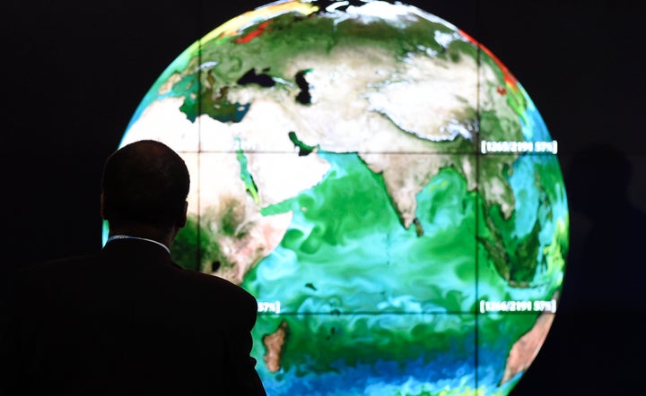 A conference attendee studies a projection of the Earth on the first day of the COP21 United Nations conference on climate change.