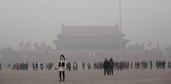 A Chinese woman wears a mask as she walks through a very hazy Tiananmen Square on a day of heavy pollution in Beijing on Nov. 30, 2015.