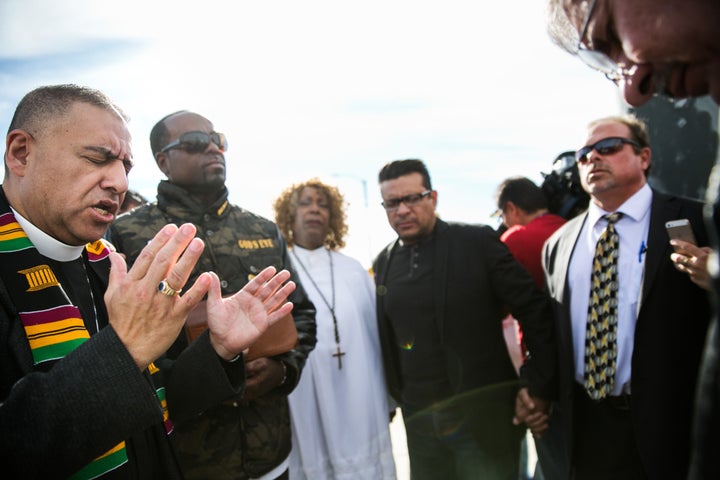 Pastor Juan Carlos Mendez, left, leads a prayer for the victims of the mass shooting at the Inland Regional Center, during a prayer vigil at Orange Show Road and Waterman Avenue on Thursday in San Bernardino, California.