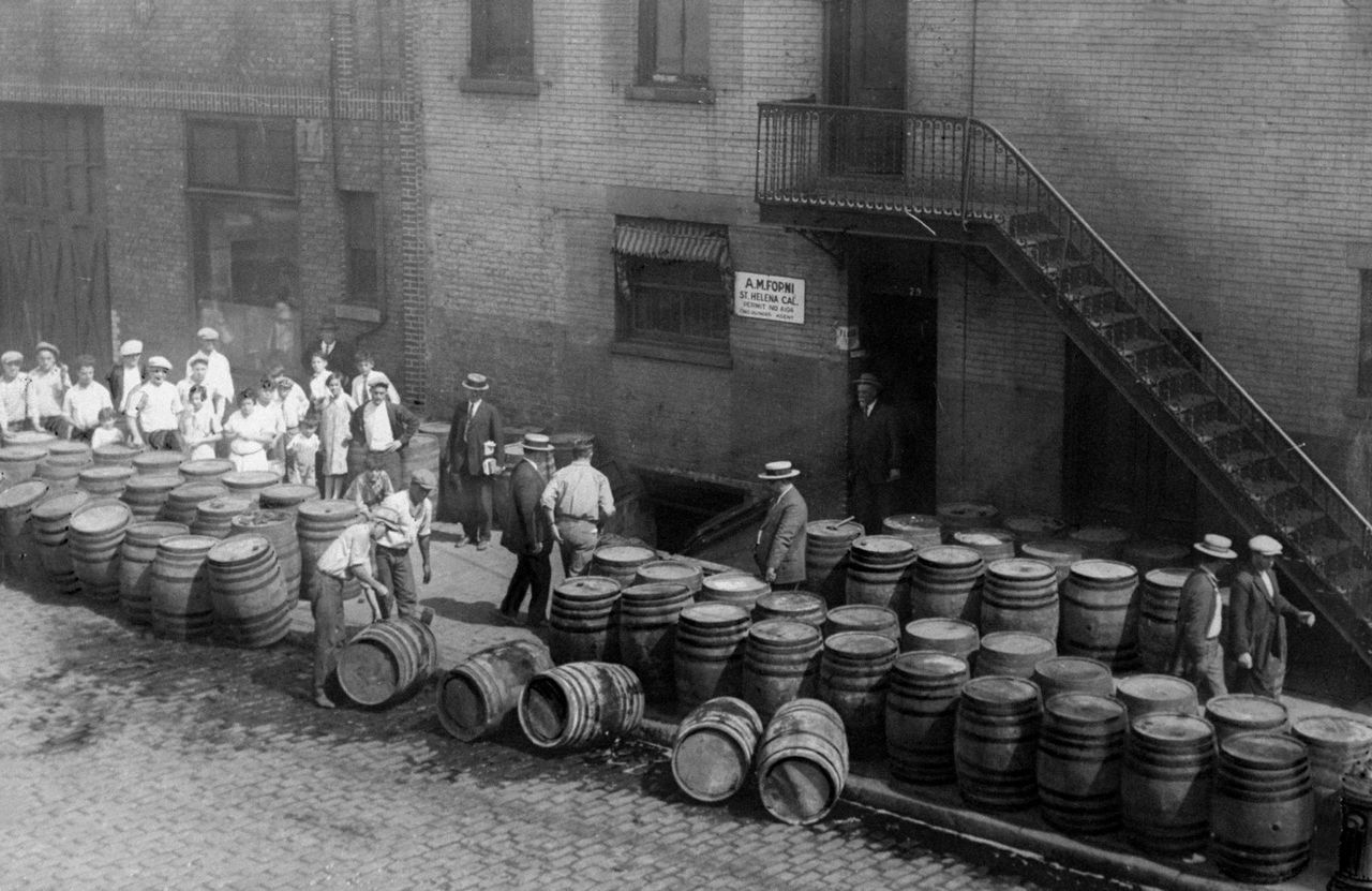 Children watch Prohibition agents and police officers destroy barrels of wine that have soured after being stored six years since the start of prohibition.