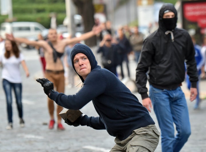 A Ukranian soccer fan readies to lob a brick towards police separating them from fans of another team prior to their Europa League match.